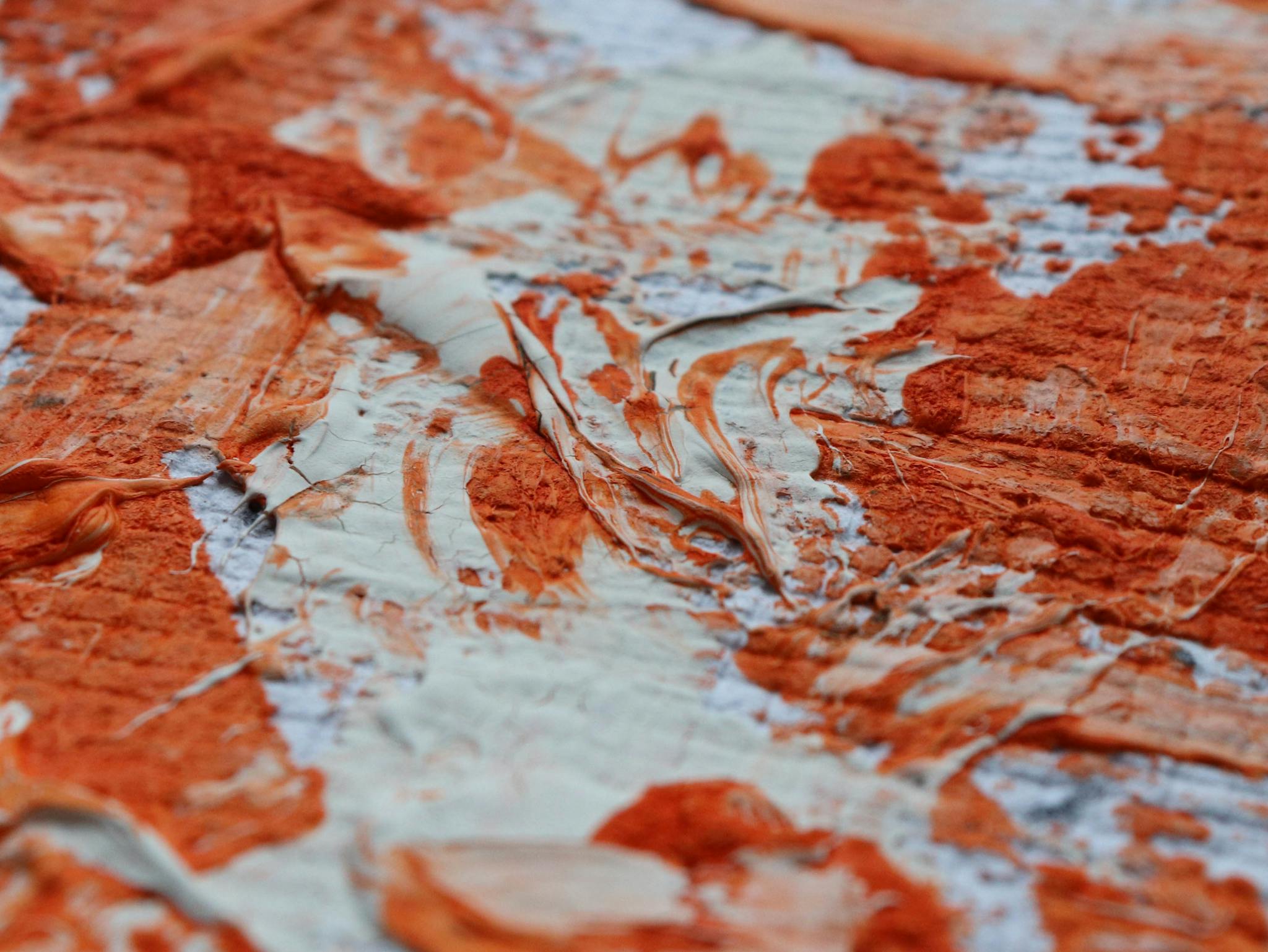 A vivid close-up of textured red and white paint creating an abstract art piece.